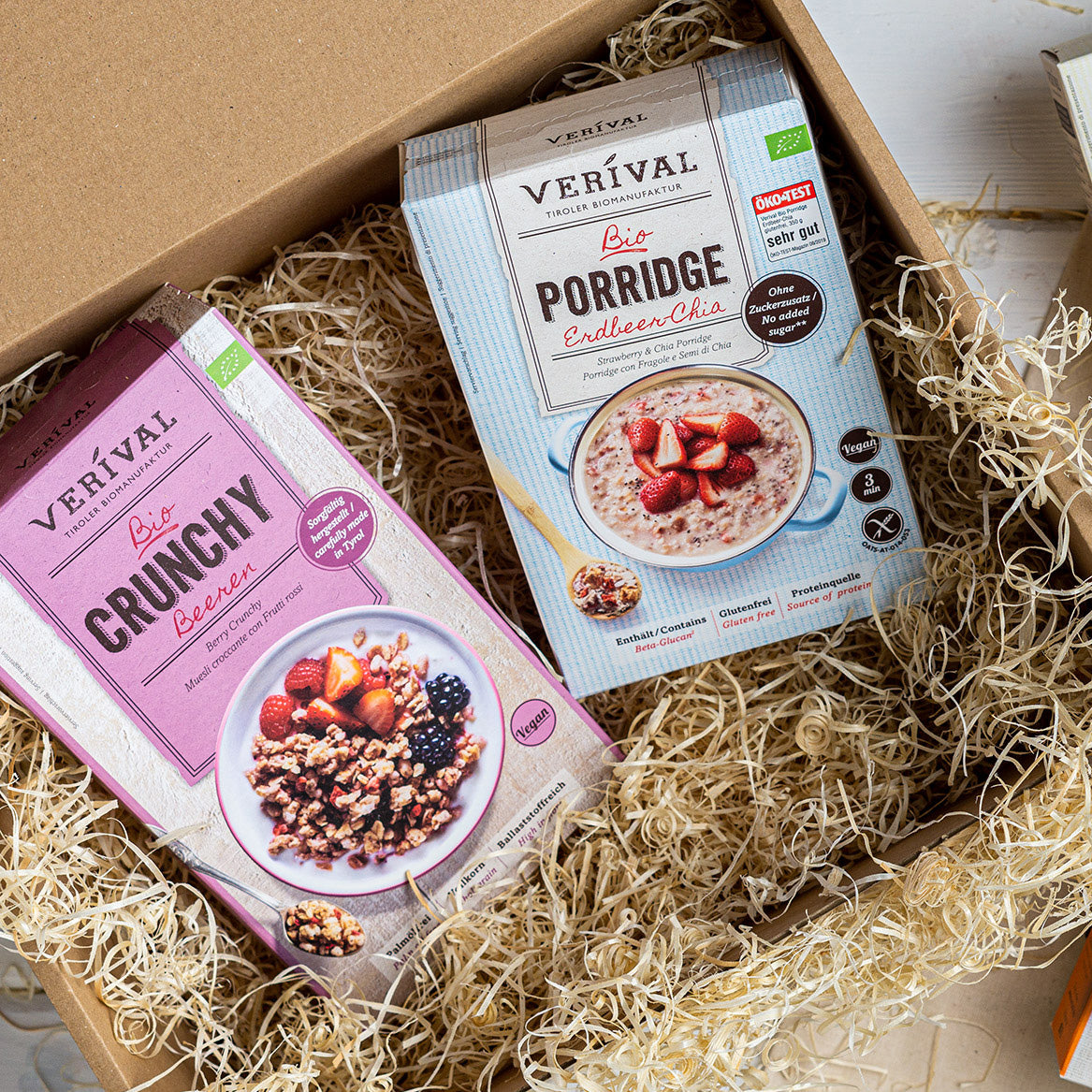Verival Granola und Porridge-Packungen liegen auf Holzwolle in einer Geschenkset-Verpackung.