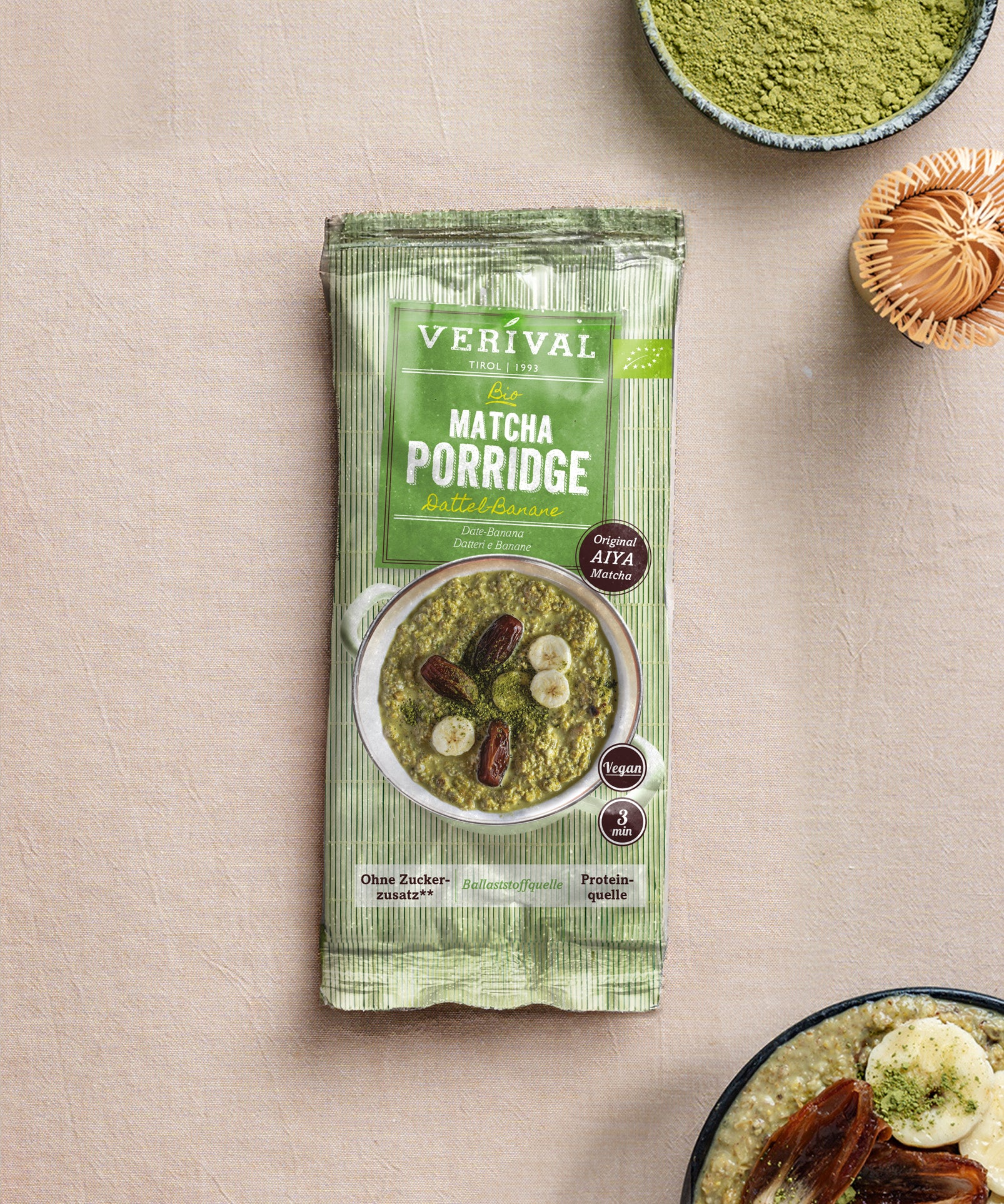 Eine „Protein Probierbox Top 10“ der Verival Bio GmbH liegt auf einem beigen Untergrund, umgeben von Schalen und Zubehör – perfekt für ein proteinreiches Frühstück ohne Zuckerzusatz.