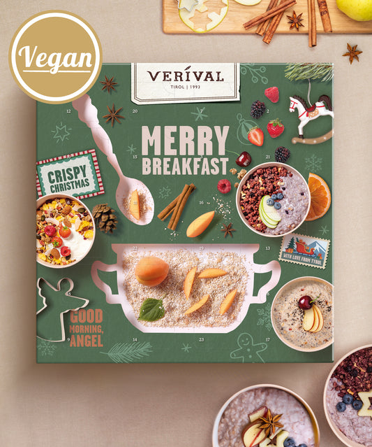 Verival Bio GmbH Adventskalender-Box: Veganes Müsli auf grünem Hintergrund mit festlichen Weihnachtsmotiven, „Bio-Frühstück“-Etikett, Müslischalen, Obst, Gewürzen und Dekorationen wie einem Schneemann, einem Lebkuchenplätzchen und einem Weihnachtsbaum.